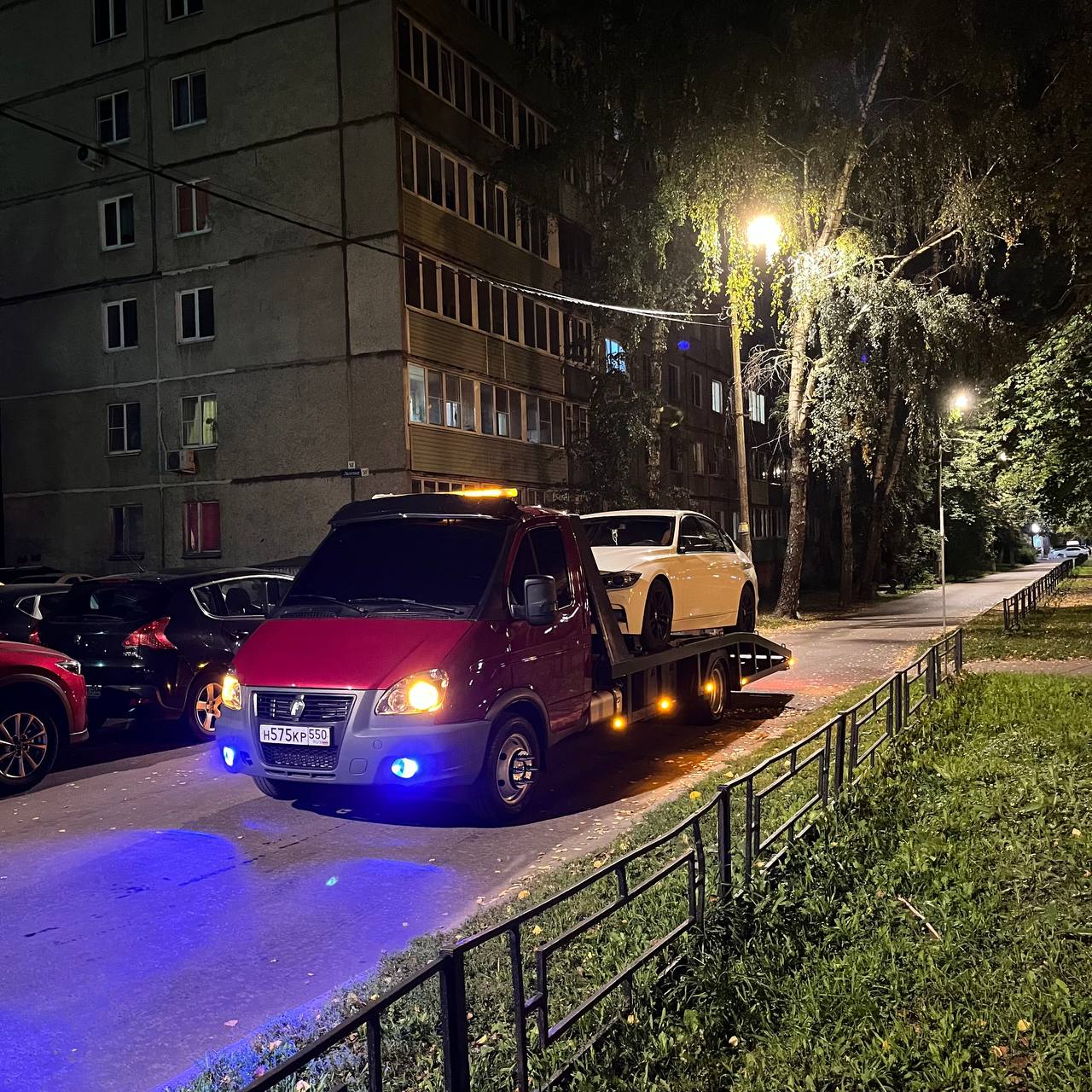 Эвакуатор с белым седаном во дворе ночью